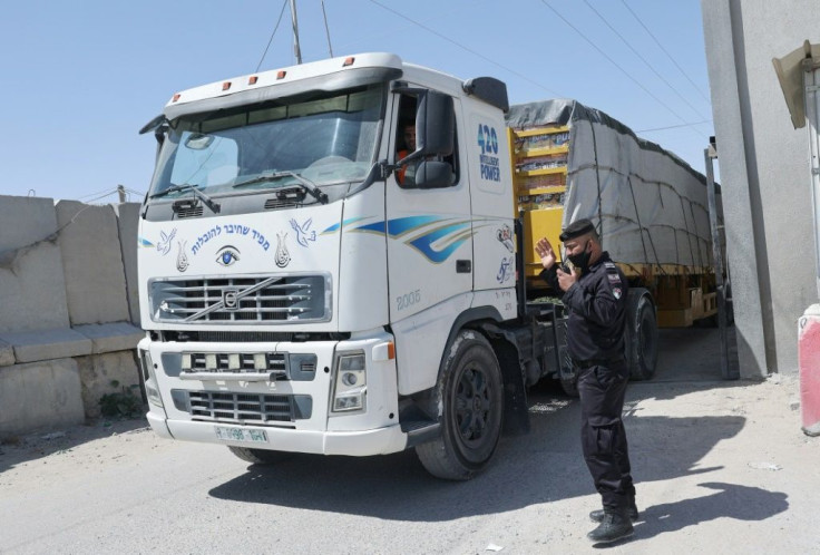 A Palestinian policeman ushers in a truck carrying goods through the Kerem Shalom crossing in Rafah, in the southern Gaza Strip, the main passage point for goods entering the enclave from Israel