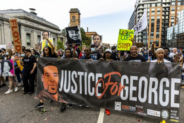 People hold signs and a banner as they march during an event in remembrance of George Floyd in Minneapolis, Minnesota