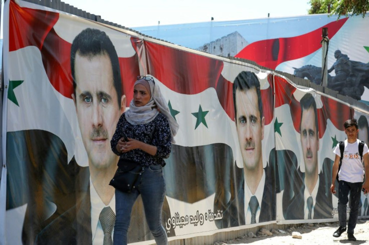 Syrians walk next to campaign billboards depicting President Bashar al-Assad in the capital Damascus, ahead of polls he is widely expected to win