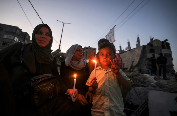Palestinian children hold candles as they visit the ruins of a building destroyed in recent Israeli air strikes in Beit Lahia in the northern Gaza Strip on May 25