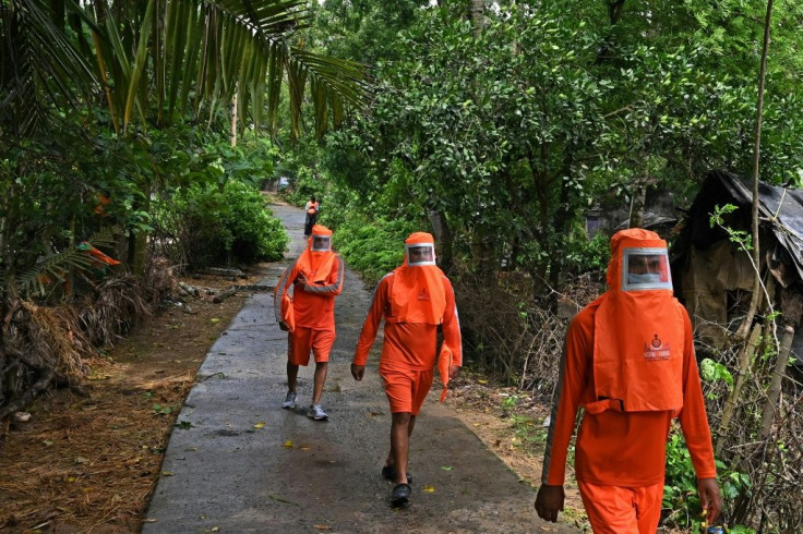 Indian disaster response workers wearing Covid protective gear urge villagers to leave their homes and go to evacuation centres