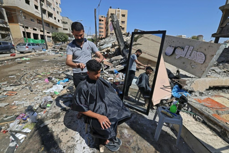 A Palestinian barber works next to the ruins of buildings and shops destroyed by Israeli strikes in Gaza