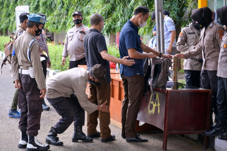 Police carry out checks on visitors to a court for the verdict of hardline Muslim cleric Rizieq Shihab in Jakarta