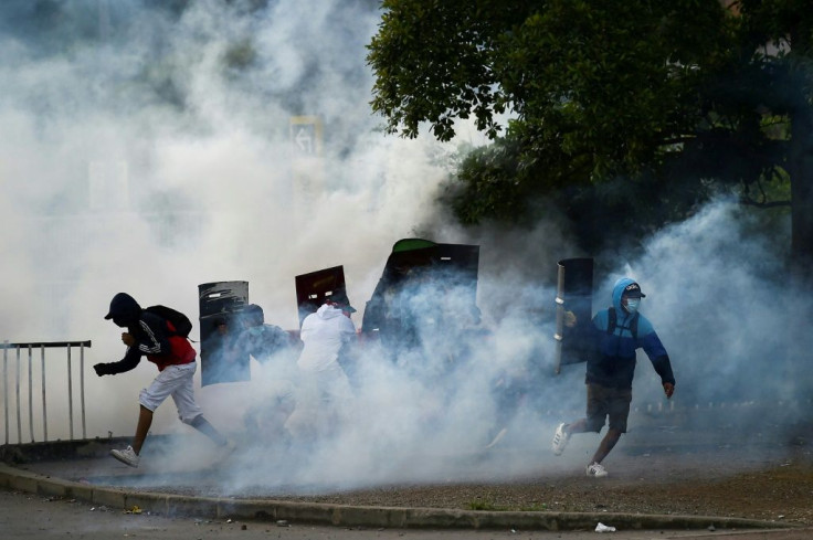 Tear gas rises around demonstrators as they clash with riot police in Cali, Colombia on May 22, 2021