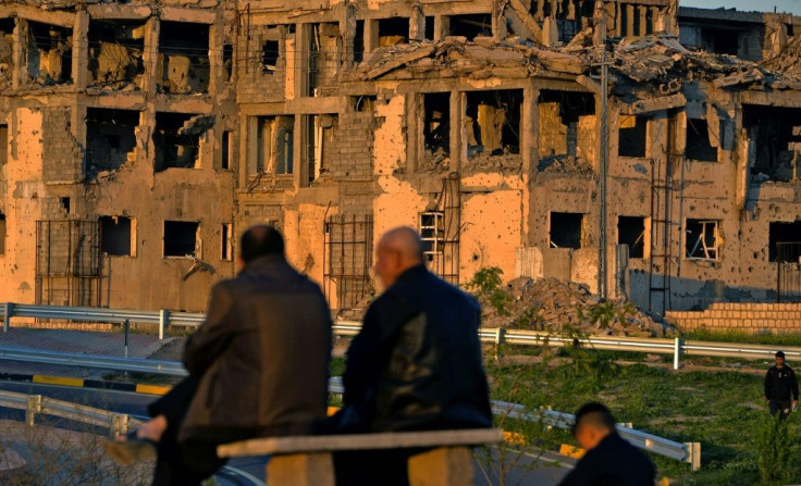 People sit in front of a Mosul building destroyed during fighting between Iraqi forces and IS jihadists in 2017