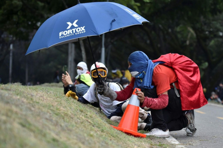 Anti-government demonstrators take cover during clashes with police in Cali, Colombia, on May 28, 2021