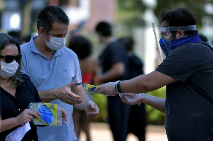 A man hands out medical masks at a rally against Brazil's President Jair Bolsonaro in Belo Horizonte