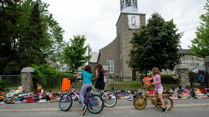 Local children of Kahnawake, Quebec stop to view the hundreds of childrenâs shoes placed in front of the St. Francis Xavier Church, in tribute to a mass grave of 215 Indigenous children found at the residential school in British Columbia, Canada