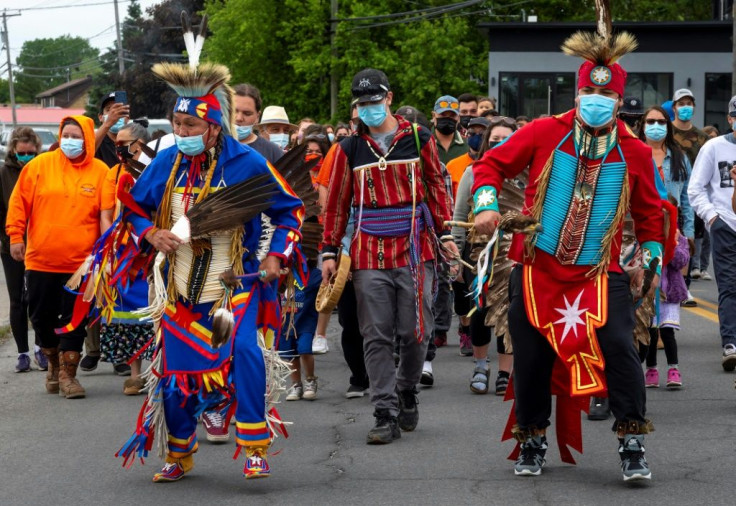 Members of the community of the Kahnawake Mohawk Territory, Quebec march through the town on May 30, 2021, to commemorate the news that a mass grave of 215 Indigenous children were found at the Kamloops Residential School in British Columbia, Canada