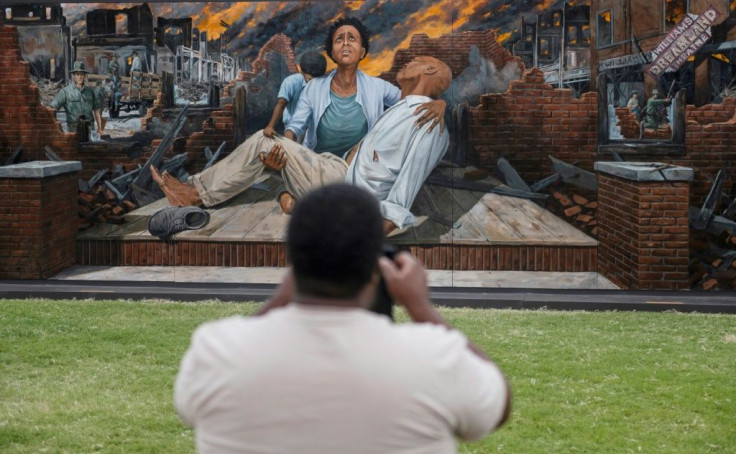 A man takes a picture of a mural in honor of victims of the 1921 Tulsa Race Massacre in Tulsa, Oklahoma