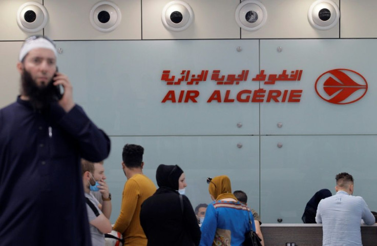 Passengers wait to check in at an Air Algeria counter for a flight to Paris at Algiers' Houari Boumediene Airport