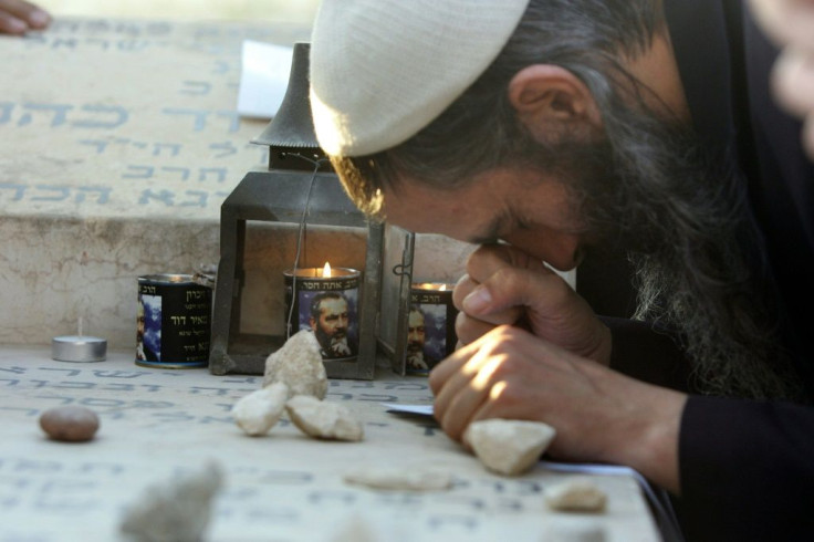 Candles burn with the image of the late rabbi Meir Kahane as a follower prays at his grave in 2006