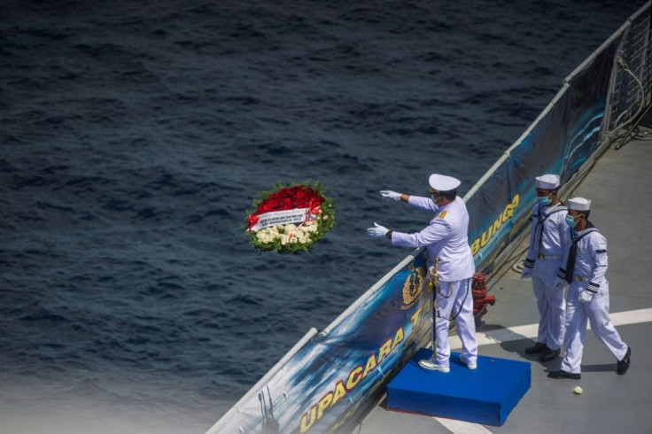 A naval officer throws a flower bouquet into the sea during a remembrance ceremony for the crew of the Indonesian submarine that sank off Bali