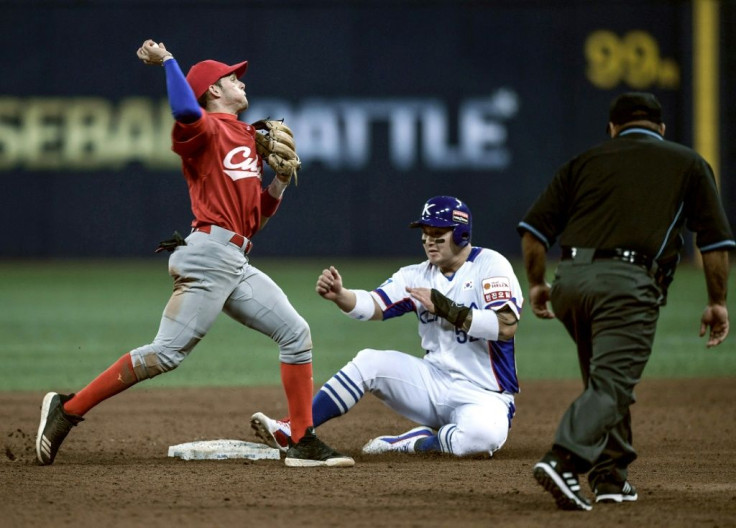 In this photo taken on November 08, 2019 Cuba's Cesar Prieto (L) throws to first base to make a double play as South Korea's Park Byung-ho (C) slides in to second during the WBSC Premier 12 Opening Round group C baseball match between South Korea and Cuba