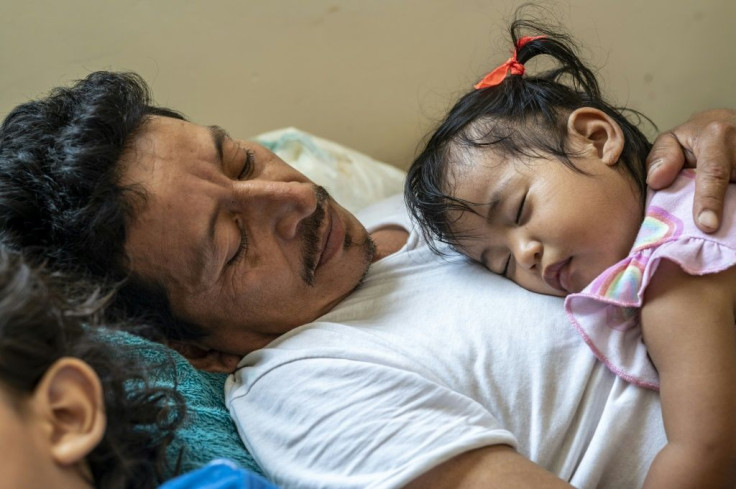 Safe haven: Migrant Jose Eliberto Hernandez Lopez lays down with his daughter Enya on his chest and his son Jose next to him at a shelter in Matamoros, Mexico