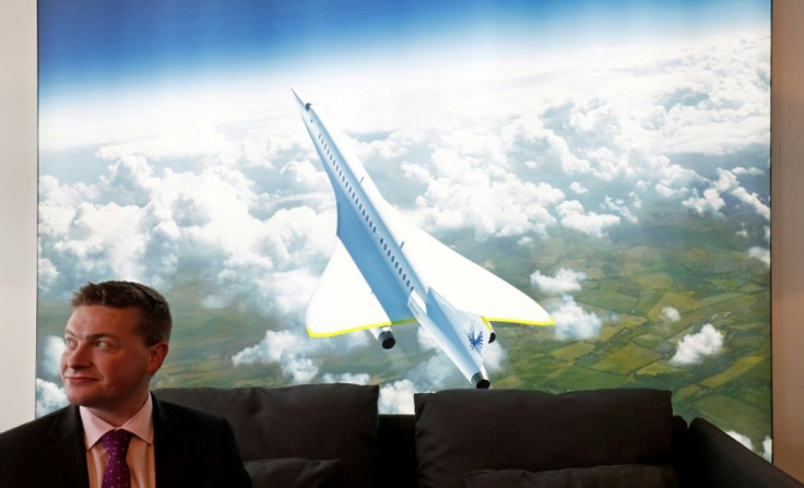Boom Supersonic co-founder Blake Scholl is shown in 2018 in front of an artists impression of his company's proposed design for a supersonic aircraft