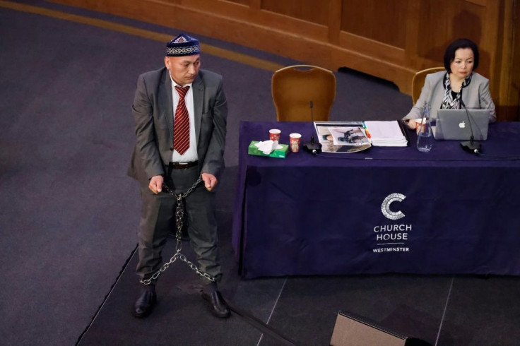 Witness Kazakh-Uyghur Omir Bekali (L) demonstrates how he says he was shackled in chains at a Uyghur re-education camp