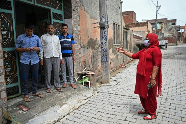 A health worker (R) speaks to a family during a vaccine awareness campaign in Kalwa village, Haryana state