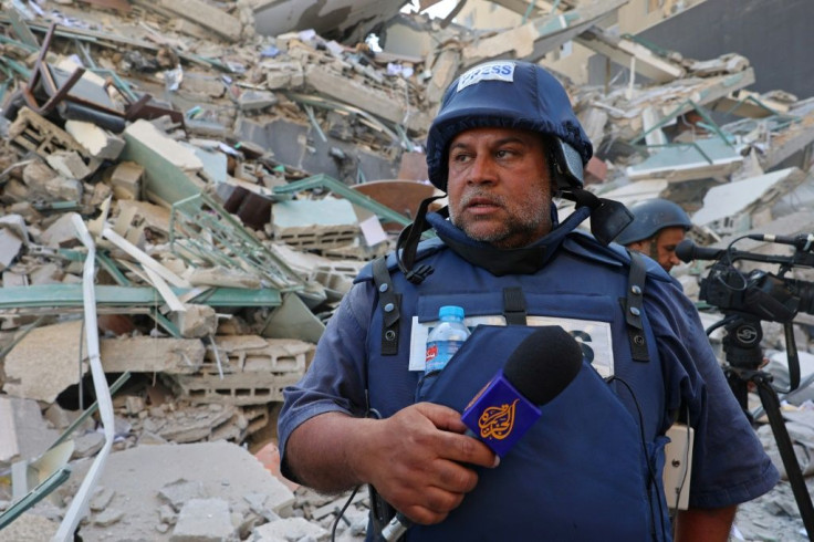 An Al-Jazeera journalist stands next to the rubble of Jala Tower, which was housing international press offices, following an Israeli airstrike in the Gaza Strip on May 15