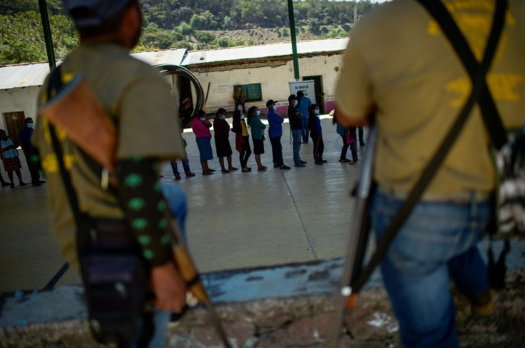 Members of a self-defense force stand guard as people vote in the community of Ayahualtempa in Mexico's Guerrero state