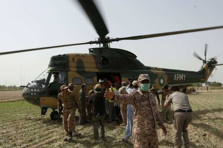 Security personnel carry an injured passenger to an army helicopter at the site of the deadlly train accident