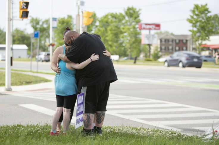 A family whose children went to school with one of the victims pay their respects at the scene