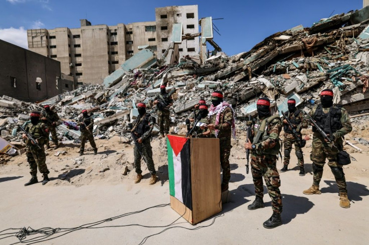 Masked fighters with the National Resistance Brigades speak outside the ruins of a Gaza tower destroyed by Israel that included the offices of the Associated Press and Al Jazeera on May 23, 2021