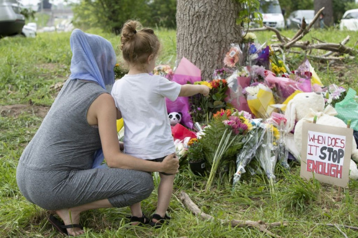 Families pay their respects on June 8, 2021, at a makeshift memorial near the site where a man driving a pick-up truck struck and killed four members of a Muslim family in London, Ontario, Canada