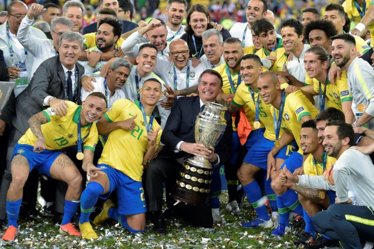 Brazilian President Jair Bolsonaro holds the Copa America trophy in July 2019 as the national team celebrate after winning the title in Rio de Janeiro