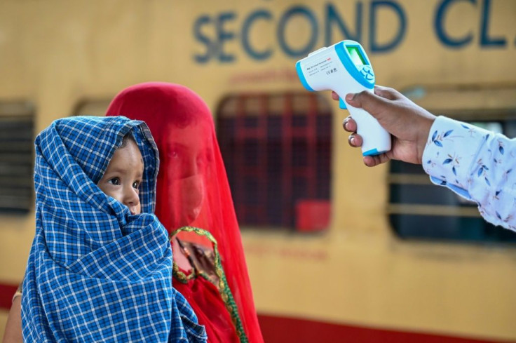 A health worker checks the body temperature of a passenger during a Covid-19 screening at a railway station in Mumbai