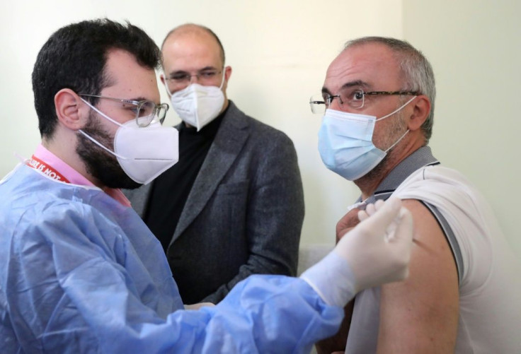 Lebanon's caretaker health minister Hamad Hassan watches as a teacher is vaccinated under the government's Covid inoculation scheme. For those who do not qualify but are ready to pledge their votes, there are politicians ready to provide the jabs