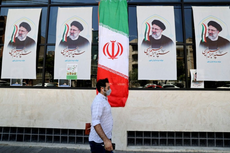 An Iranian man walks by posters of presidential candidate Ebrahim Raisi outside a campaign office in Tehran on June 7