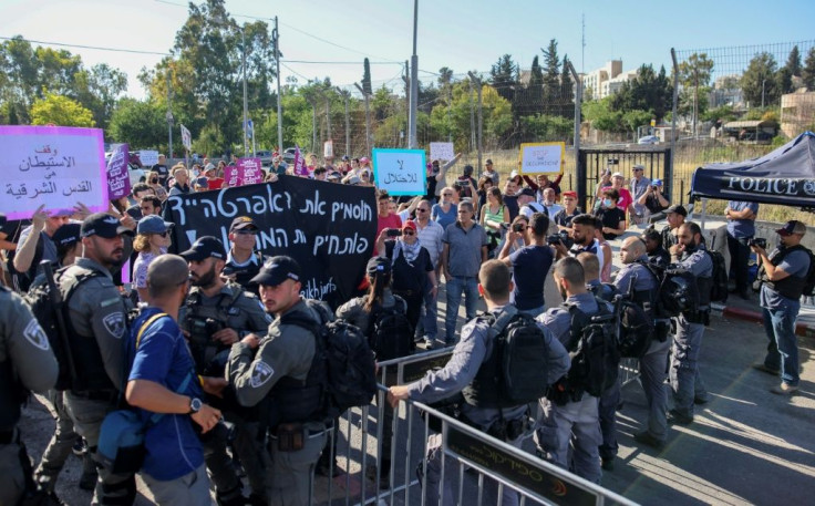 Palestinian, Israeli, and foreign activists hold up signs reading "no to the occupation", and "stop apartheid", as they approach Israeli guards during a demonstration in Sheikh Jarrah on June 4