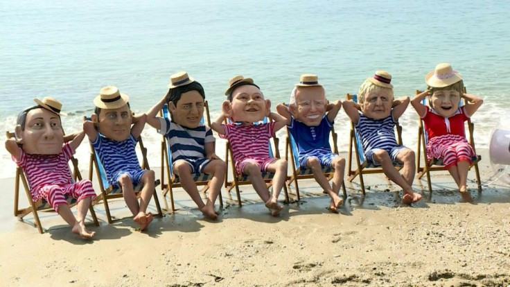 Campaigners from UK-based anti-poverty organisation Oxfam pose as G7 leaders wearing swimsuits and relaxing on deckchairs
