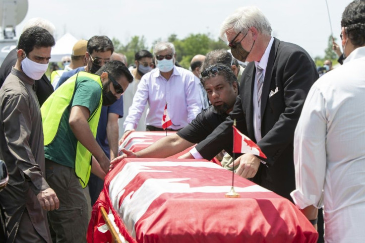 Pallbearers move the caskets of four members of the Afzaal family at the Islamic Centre of Southwest Ontario on June 12, 2021