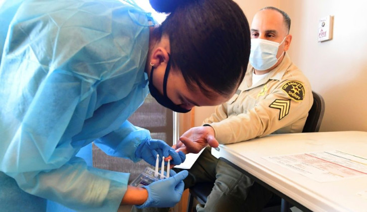 A phlebotomist takes blood through a finger prick during a Covid-19 antibody test