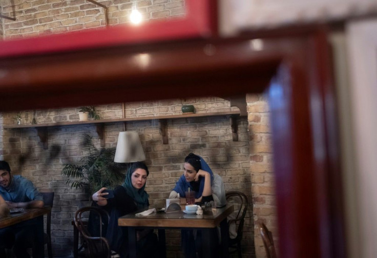 Two Iranian women take a selfie while sitting at a cafe in Tehran on June 14, 2021