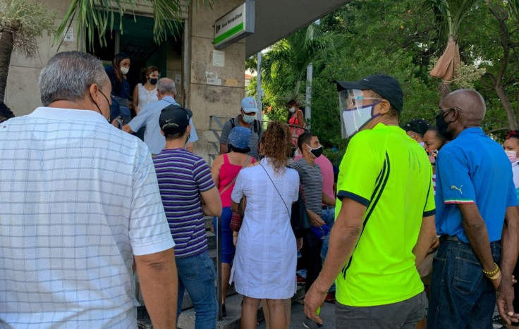 People line up outside a bank branch in Havana on June 11, 2021, to deposit US dollars before the government put into effect a new decree that suspended such deposits in the country's banks