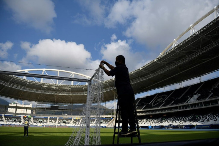 An employee installs the goal net at one end of the Nilton Santos Olympic stadium in Rio de Janeiro ahead of a Copa America match June 16, 2021