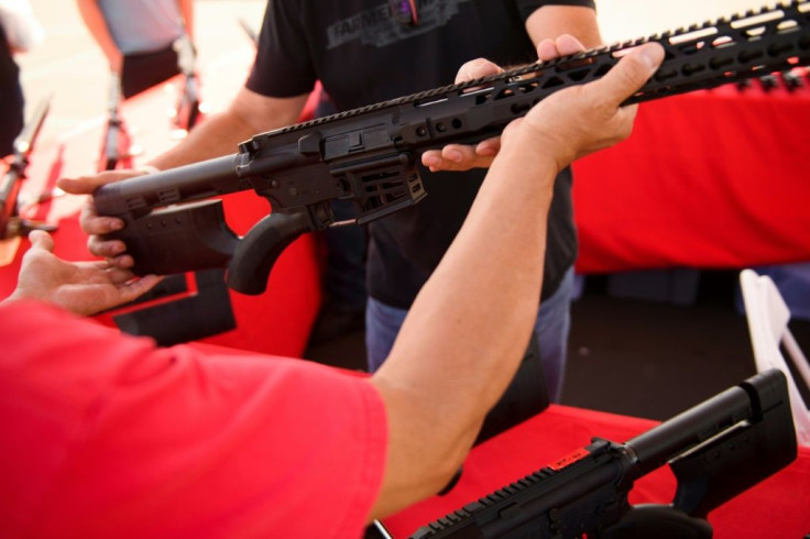 A clerk hands a customer an AR-15 style rifle from TPM Arms LLC on display for sale at the company's booth at the Crossroads of the West Gun Show at the Orange County Fairgrounds on June 5, 2021 in Costa Mesa, California