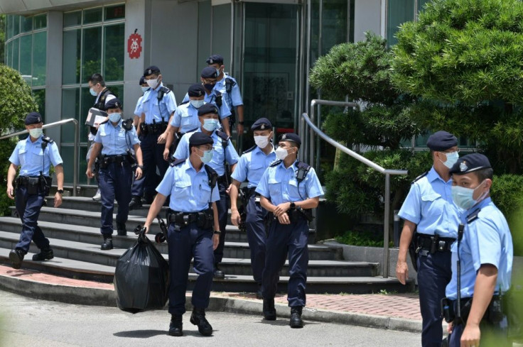 Police officers leave the Apple Daily newspaper offices in Hong Kong