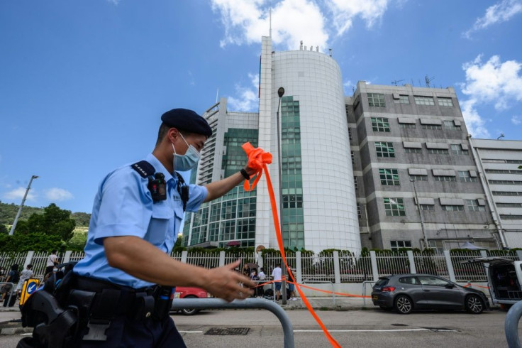 A police officer removes a cordon from across the road outside the offices of Apple Daily after the raid