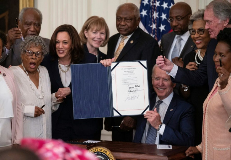 US Vice President Kamala Harris and Opal Lee (2nd L), the activist known as the grandmother of Juneteenth, watch as US President Joe Biden holds the signed Juneteenth National Independence Day Act, in the East Room of the White House