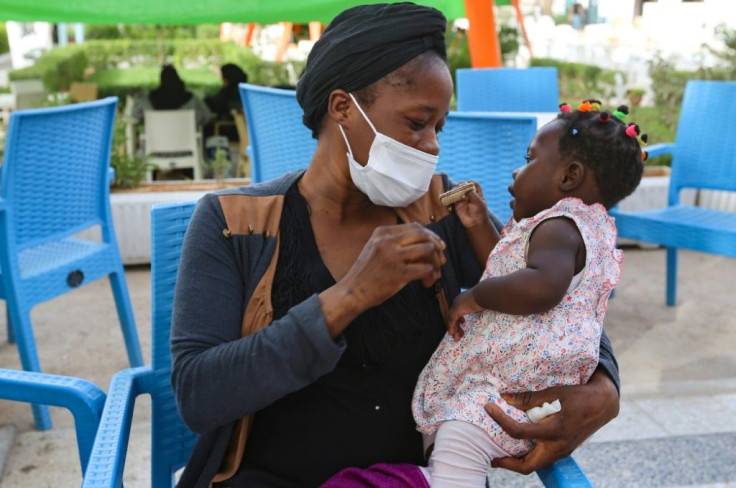 Aisha, a migrant from Guinea, plays with her baby daughter at a park in the Tunisian town of Medenine