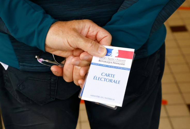 A voter waits with his electoral card to cast his ballot at a polling station in Cucq, Northern France, for the first round of the French regional elections