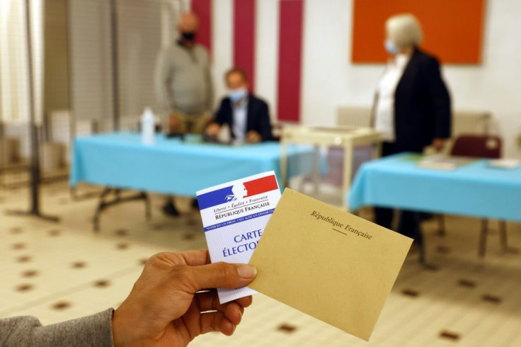 A voter shows an electoral card and a ballot envelop at a polling station in Cucq, northern France