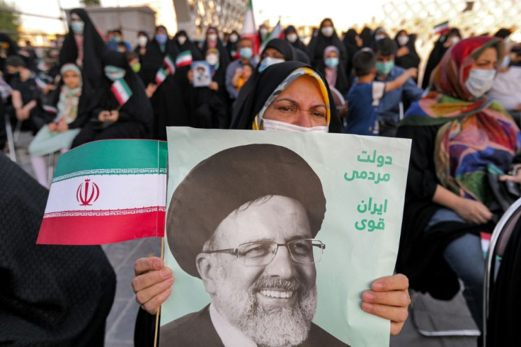 A woman holds a poster of Iran's newly-elected president Ebrahim Raisi, with text in Persian reading "government of the people, strong Iran", as supporters celebrate his victory in Imam Hussein square in the capital Tehran on June 19, 2021
