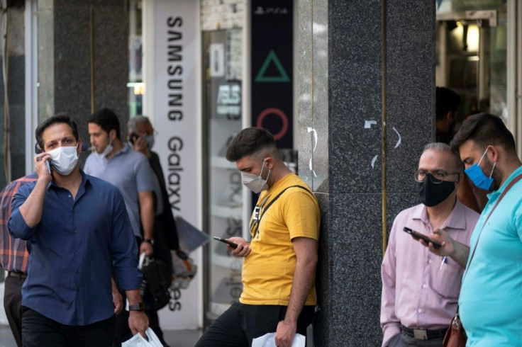 Iranian men check their smartphones in front of a shopping mall in northern Tehran on June 19, 2021