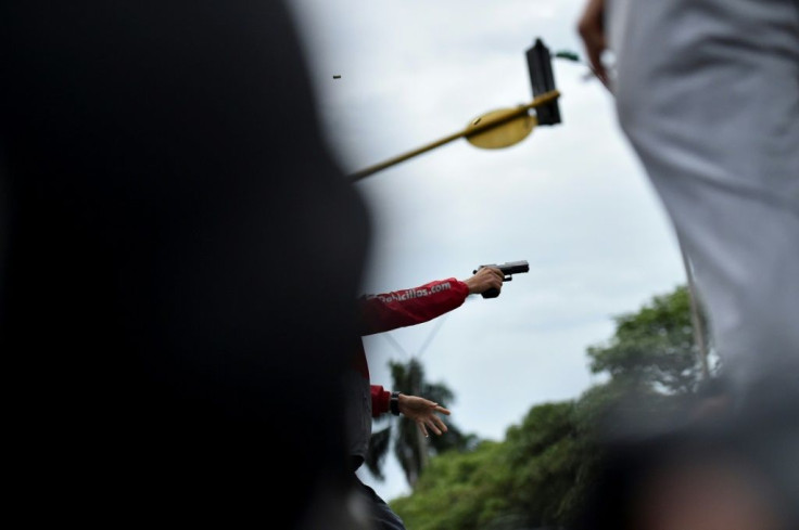 A man fires a gun during a clash between demonstrators and police on May 28, 2021