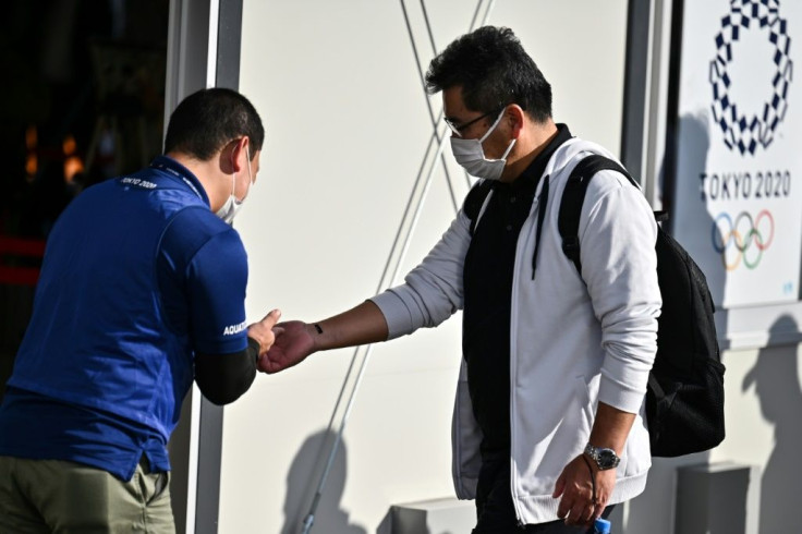 A volunteer checks the body temperature of a volunteer acting as a spectator during a test of potential spectator and games screening measures